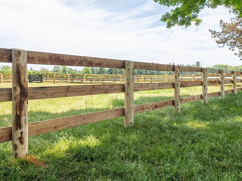 Three rail timber fencing across grassy field