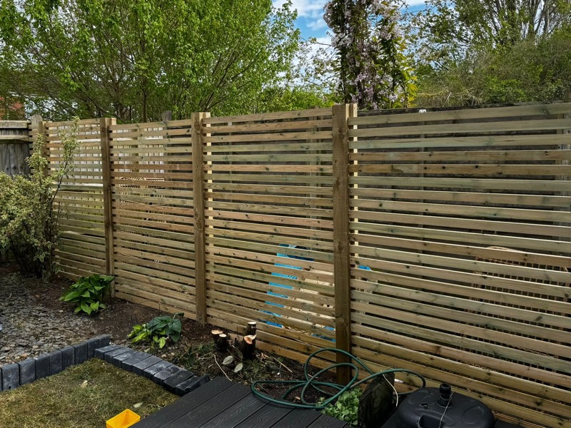 Modern horizontal slat timber fence in garden setting