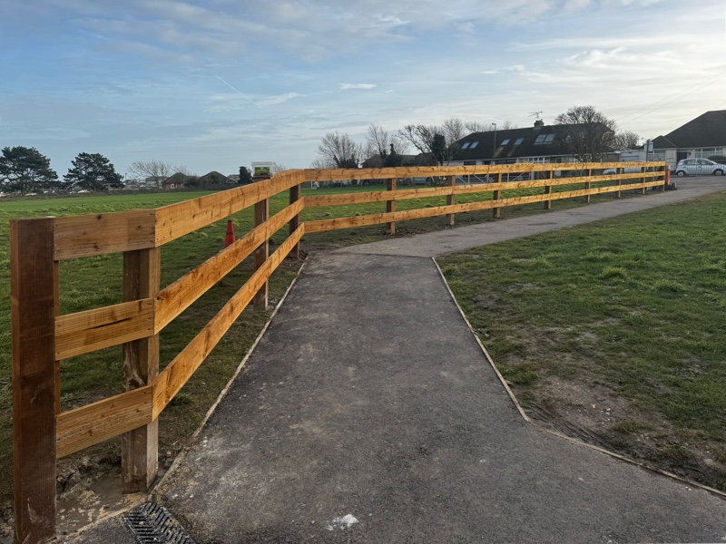 Rustic wooden post and rail fence alongside pathway
