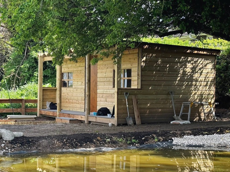Ranch style cabin by a pond and surrounded by trees